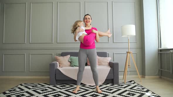 Happy Woman Doing Sit-ups with Daughter in Hands