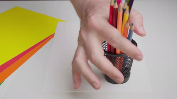 The Artist Puts Colored Pencils in a Stand