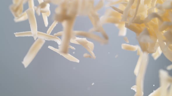 Flying grated mozzarella cheese in the air. Slow Motion.