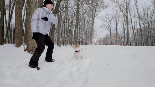 Happy Girl with Dog Running Along in Park Winter