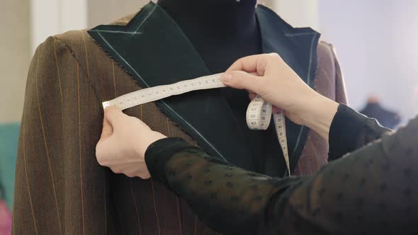 Tailor Taking Measures with Measuring Tape on a Mannequin