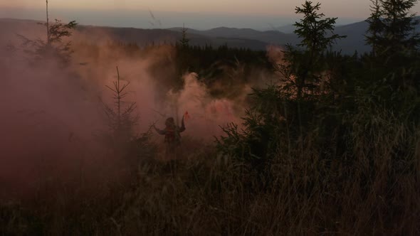 Young Woman and Man Running Through Colorful Smoke in Mountains at Sunset