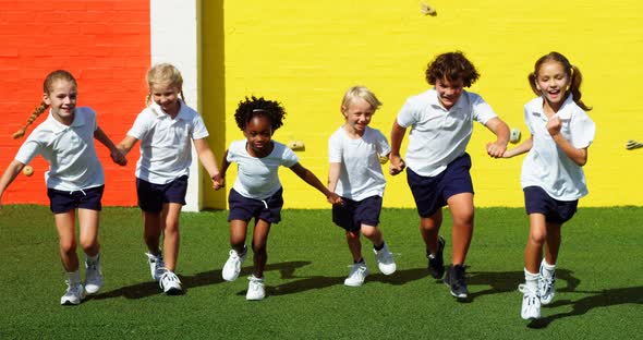 School kids holding hands and running in campus