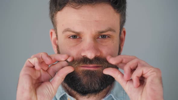 Portrait of a Handsome Bearded Man Twists His Mustache