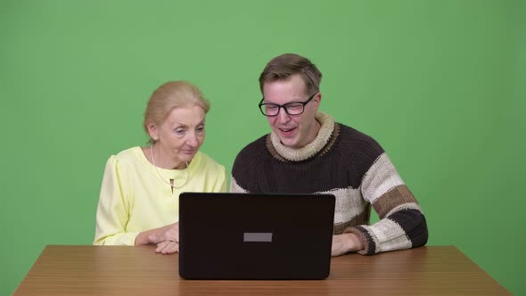 Senior Businesswoman and Young Handsome Man Working with Laptop Together