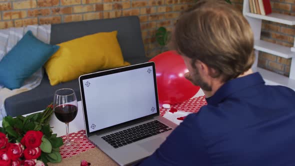 Rear view of caucasian man waving on videocall at home