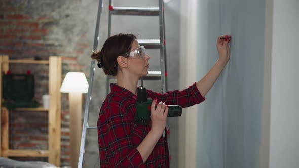 Woman with Goggles Prepares to Screw Fastening in Room