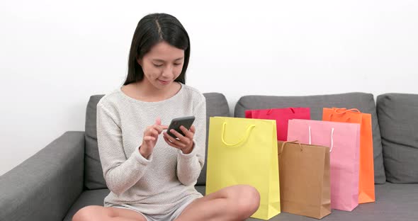 Woman Using Mobile Phone for Online Shopping with Lots of Paper Bag at Home