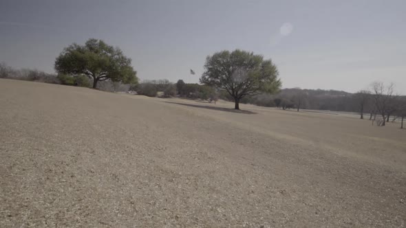 This is a moving shot of an open field in a Park. You can see the American flag blowing in the wind