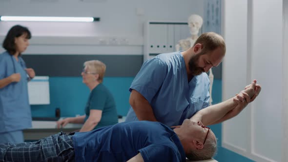 Physiotherapist Assisting Elder Patient to Stretch Arms Muscles