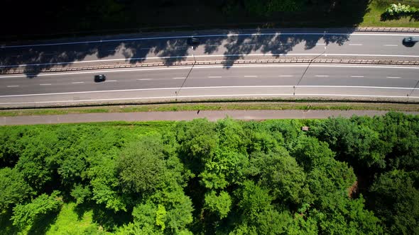 Top-Down Shot Of Cars Driving On Highway Next to Green Forest. Aerial View.