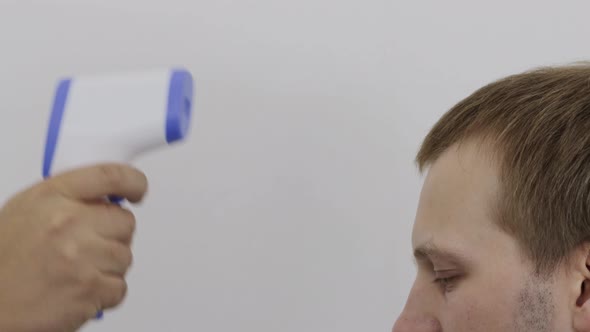 Measuring Body Temperature with an Electronic Thermometer in a Caucasian Man on a White Background