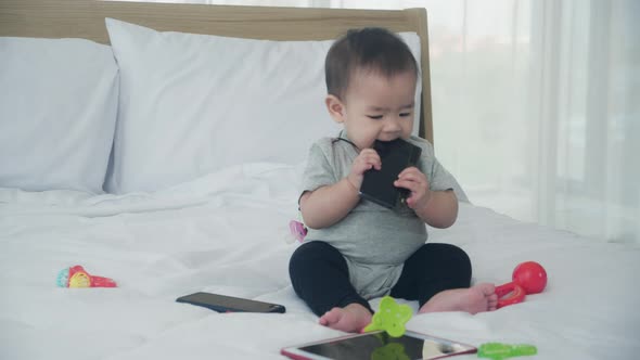 Portrait of cute baby girl sitting on bed at bedroom, happy of toddler is positive.