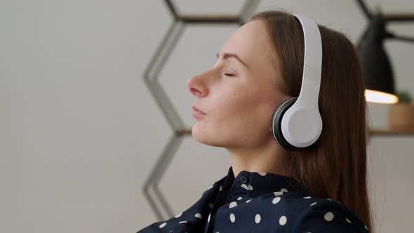 Closeup of a Woman Listening to Music with White Headphones Sitting on the Couch