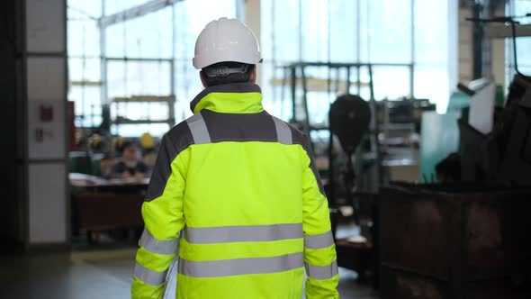 Engineer in Hard Hat is Walking Through Factory