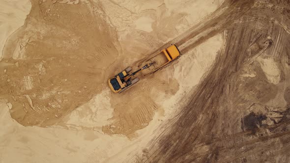 Excavator loading sand into a dump truck in opencast sand quarry