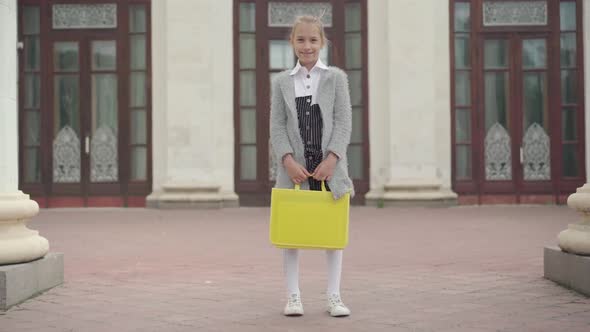 Wide Shot of Happy Girl Standing Outdoors at School Entrance. Camera Approaches To Smiling Cute