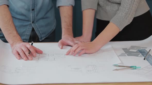 Close Up Hands of Two Workers Discussing Building Drawings in Office. Closeup Shooting of Arms