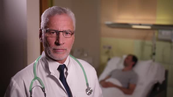 Portrait of Serious Aging Doctor in Patient's Ward