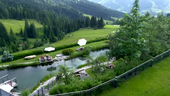 Tilt up shot of relaxing people at natural lake of luxury hotel surrounded by Austrian mountains in