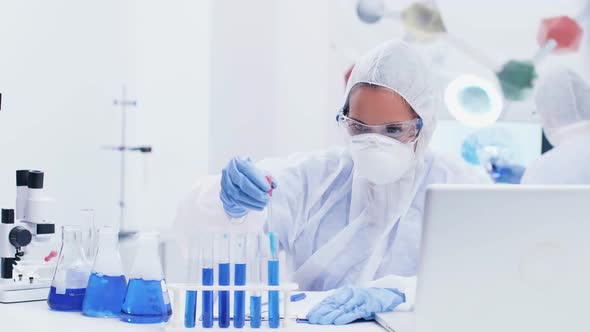 Female Scientist in Modern Laboratory Wearing a Coverall Equipment Taking Samples