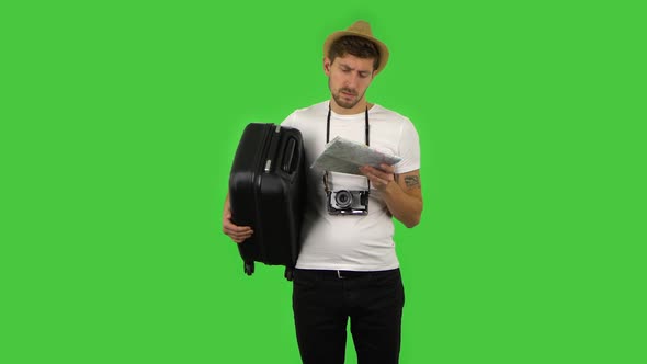 Tourist with Suitcase Carefully Examines Map, Then Looking at Camera with Shocked Facial Expression