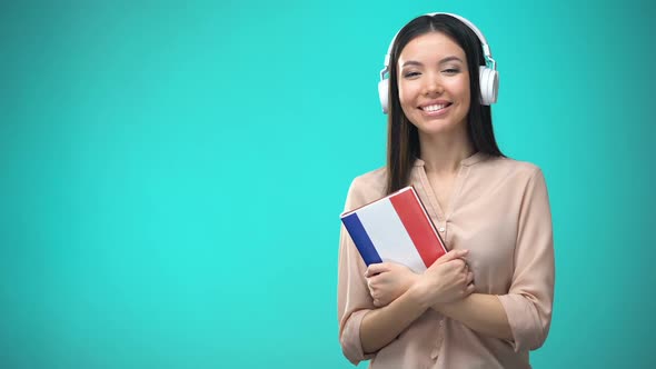Girl Listening French Audio Lessons in Headset, Book in Hands, Translations