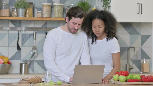Mixed Race Couple Working on Laptop in Kitchen