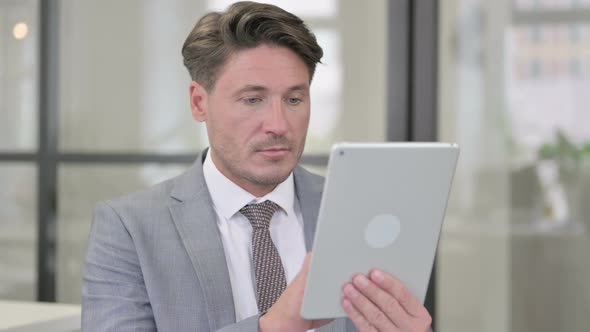 Attractive Middle Aged Man using Tablet in Office