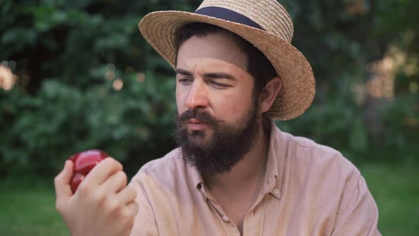 Closeup of Young Male Farmer Looking at Green and Red Bell Pepper Smelling Organic Vegetable Smiling