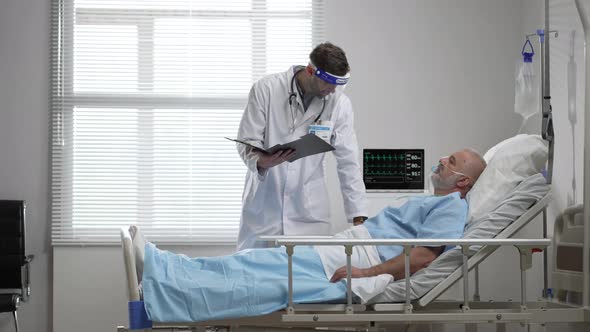 Young Doctor Talking to Senior Woman Resting in Hospital Bed