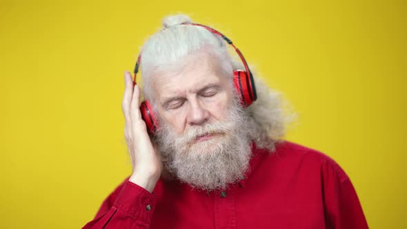 Headshot Portrait of Relaxed Cheerful Senior Man in Headphones Dancing on Yellow Background