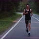 Athlete in a Sports Uniform Runs Along an Asphalt Road Track in the Forest - VideoHive Item for Sale