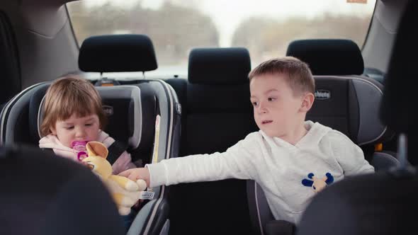 Children Play with Toys While Traveling with the Family in the Car