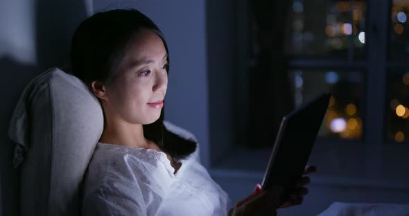 Woman watching on digital tablet at night