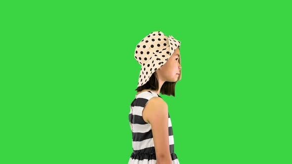 Little Asian Girl in a Sundress and a Hat Posing with Shopping Bags on a Green Screen Chroma Key