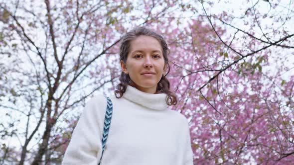 Portrait of Pretty Girl in Park with Blooming Japanese Sakura Trees