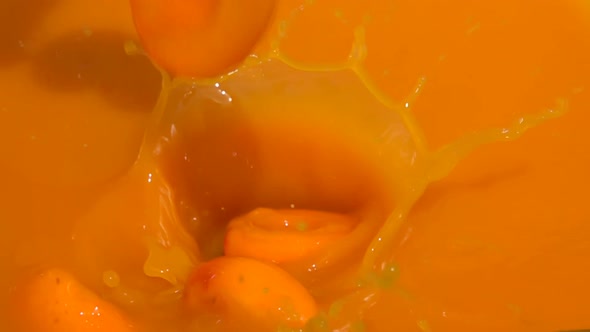 Wet Apricot Halves are Falling Into the Fresh Juice with Beautiful Splashes