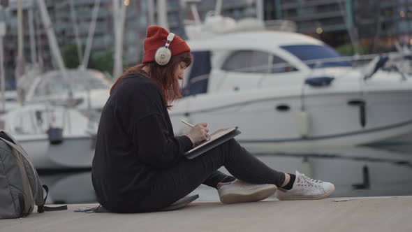 Girl in Hat Work Networks on the Tablet in a Summer Marina on the Sunset