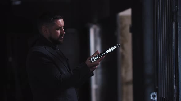 Adult Man Holding a Gun in His Hands and Looking Over It