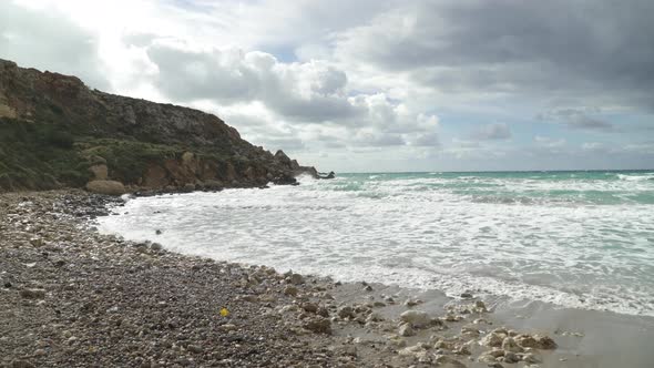 Piles of Rocks On a Golden Bay Beach with Mediterranean Sea Waves Crashing on Sandy Shore