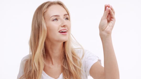 Young Beautiful Caucasian Blonde Girl Picking Imaginary Items From Air Then Blowing Them From Palms