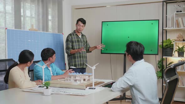 Asian Man Engineer With Solar Cell Presenting About The Green Screen Tv At The Office