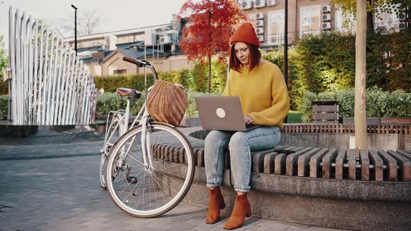 Young Woman Sitting on Bench in City Park Working Online on Notebook Finishing Work Closing Laptop