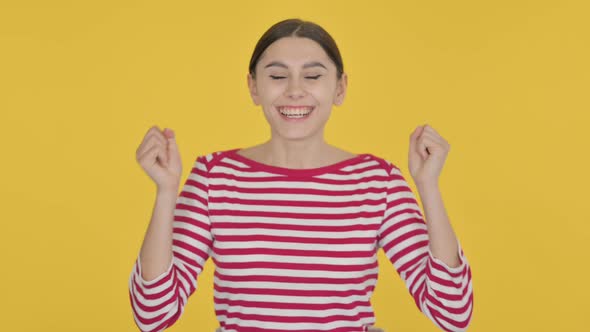 Excited Spanish Woman Celebrating Success on Yellow Background