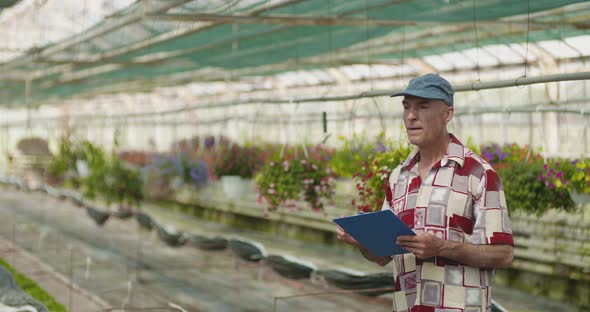 Researcher Examining Potted Plant At Greenhouse