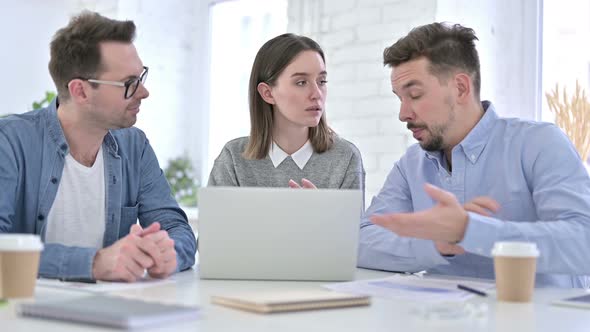 Serious Creative Team Discussing and Working on Laptop