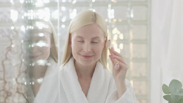 Pretty Female Doing Facial Massage in Bright Bathroom