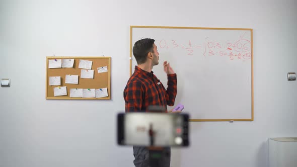 Math Teacher Explains Online Lesson To Students Using Marker and White Board