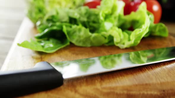 Vegetables and kitchen knife on wooden table